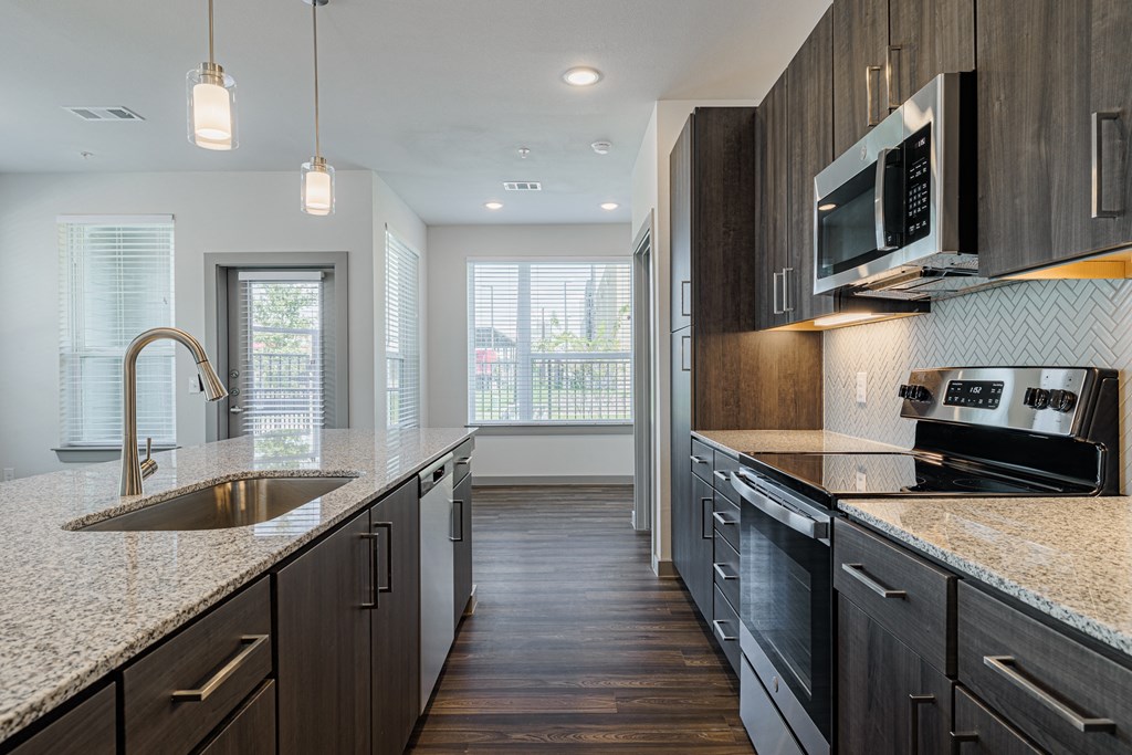 a kitchen with granite countertops and dark wood cabinets
