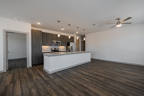 A modern kitchen with dark wood floors and a white island.
