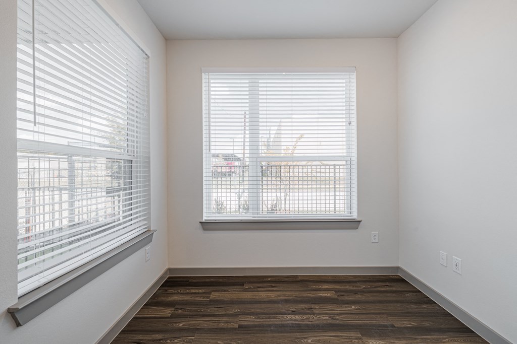 a bedroom with two windows and a hardwood floor