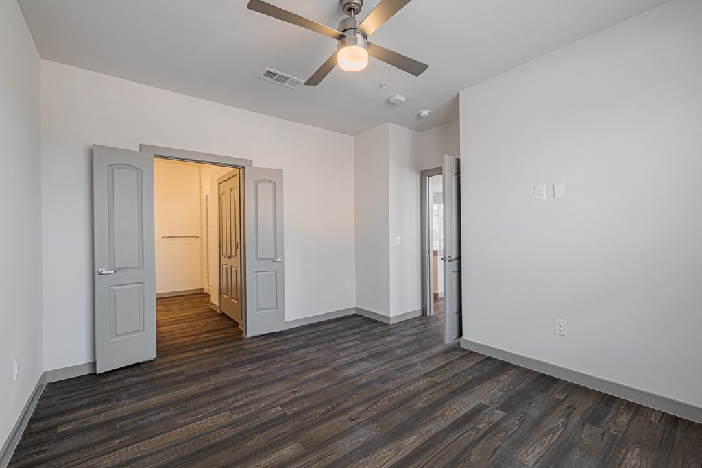 a bedroom with white walls and a ceiling fan