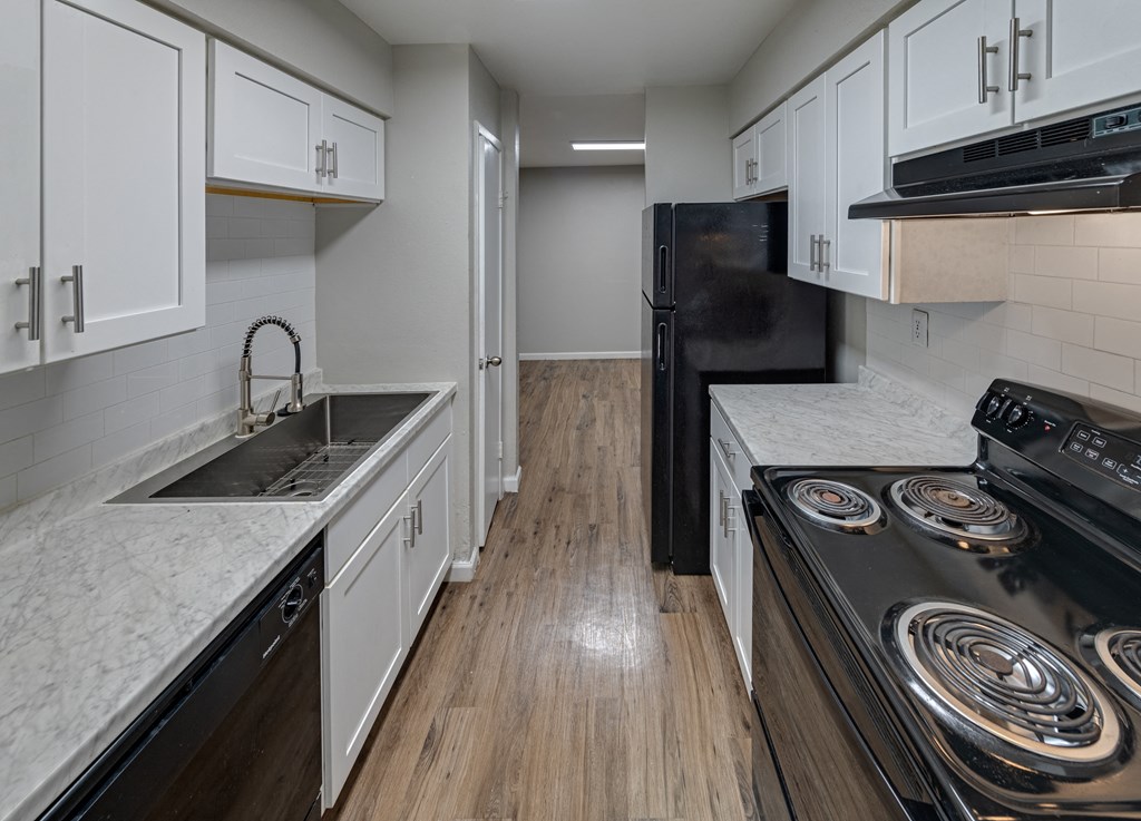 a kitchen with white cabinets and stainless steel appliances and a black refrigerator