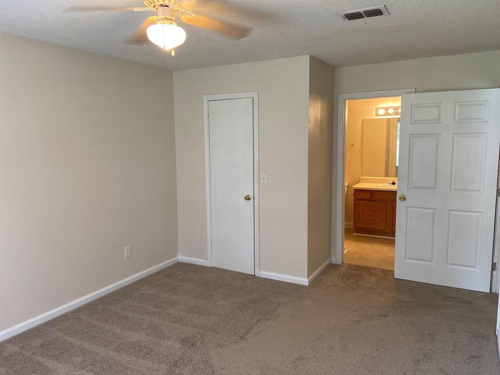 a bedroom with a carpeted floor and a ceiling fan