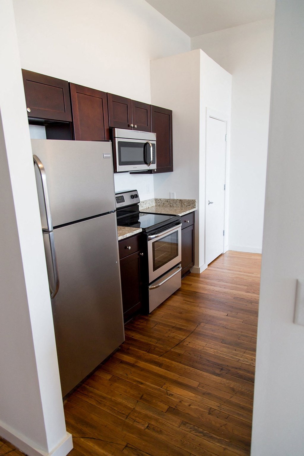 a small kitchen with stainless steel appliances and a wooden floor