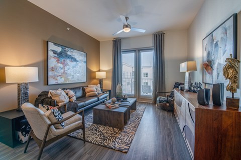 A living room with a chair, a couch, a coffee table, and a painting on the wall.