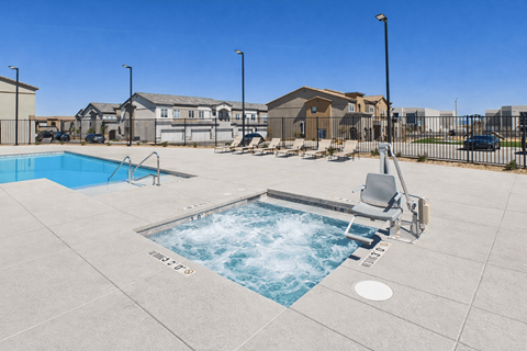 A small pool with a slide in the middle of a concrete patio.