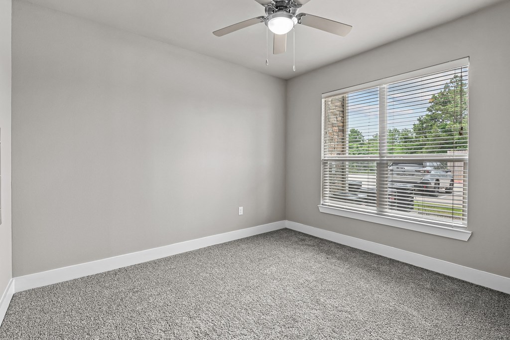 an empty room with a window and a ceiling fan