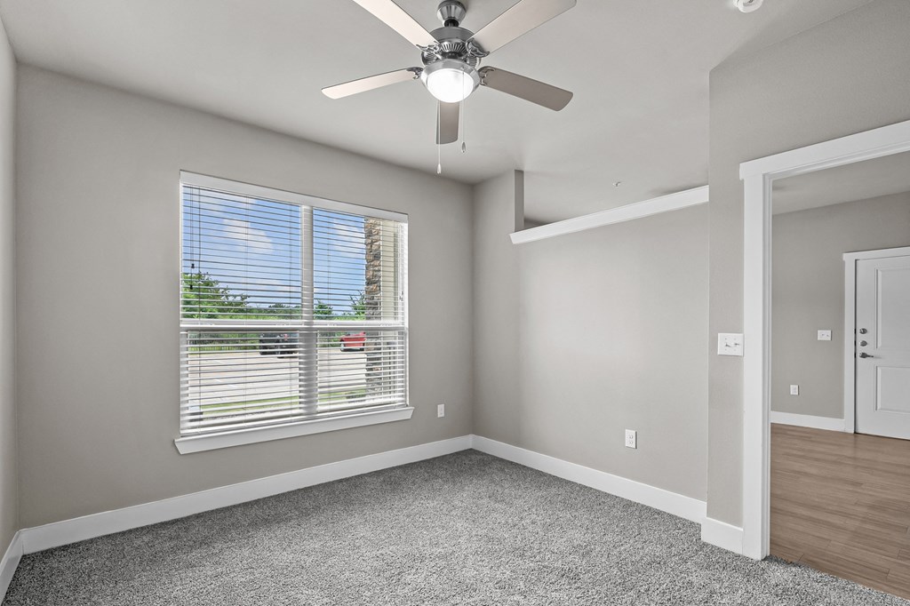 an empty bedroom with a ceiling fan and a window