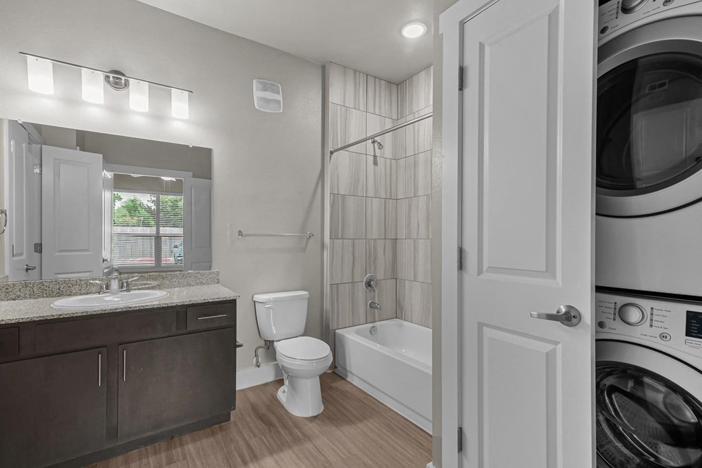 a white bathroom with a washer and dryer and a toilet and a sink