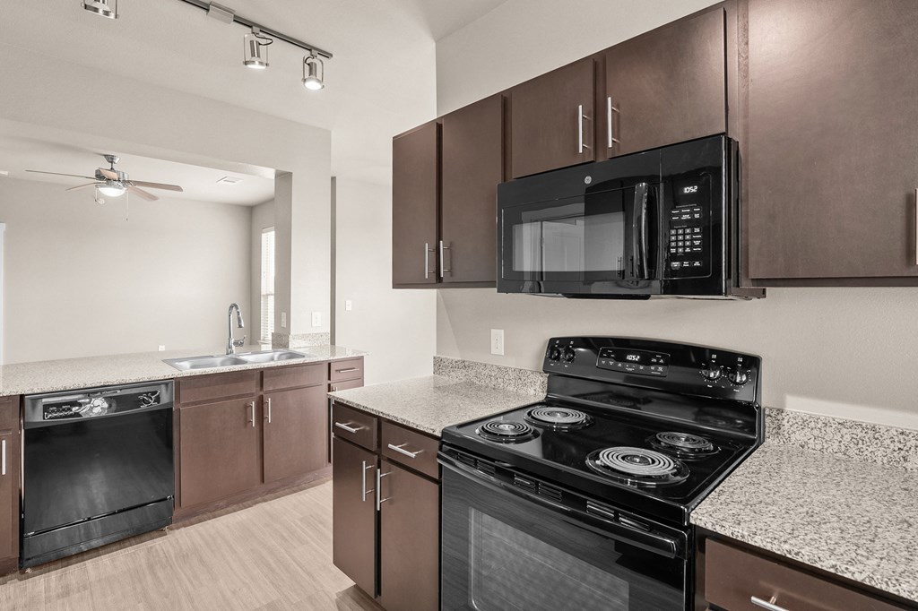 an empty kitchen with black appliances and granite counter tops