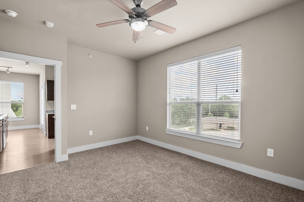 an empty living room with a ceiling fan and a large window