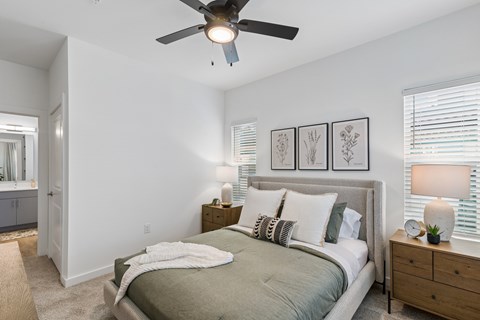 A bedroom with a bed, nightstands, and a ceiling fan.
