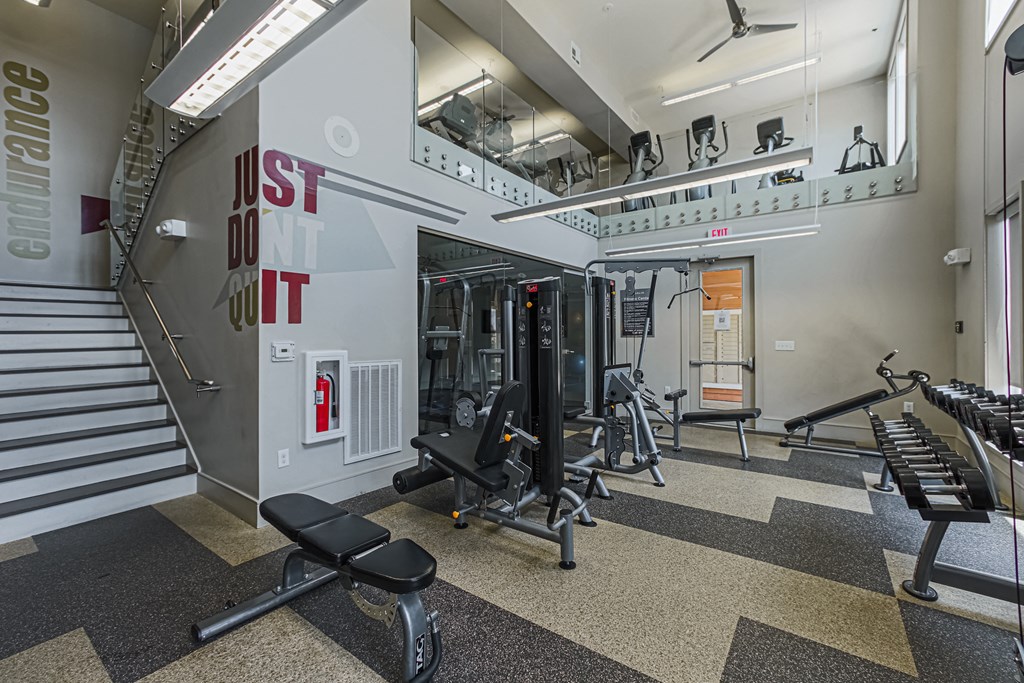 a view of the fitness center with weights machines and a staircase in the background
