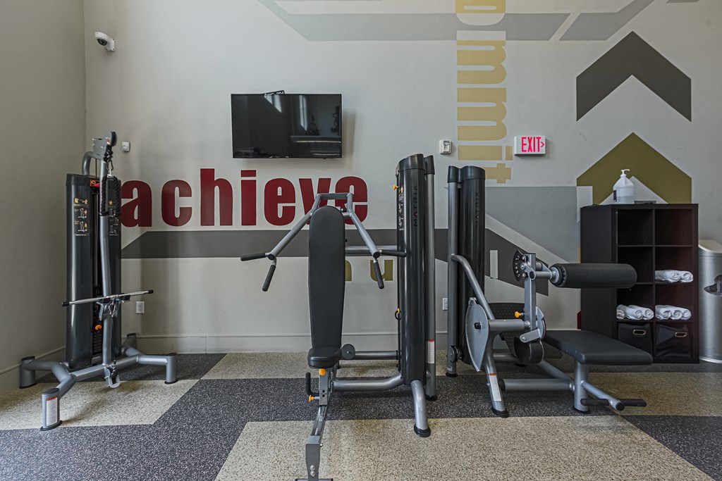a gym with exercise equipment and a tv on the wall