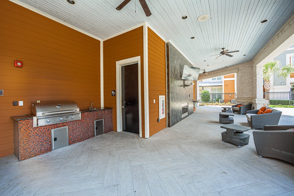 a covered patio with a grill and seating area