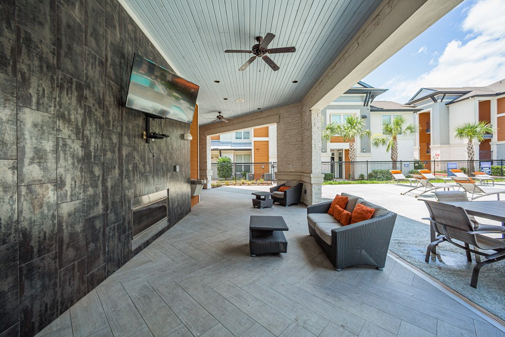 a patio with couches and chairs and a flat screen tv on the wall