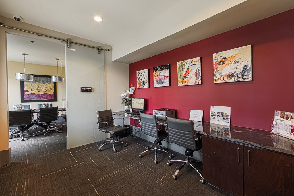 a room with a red wall and a long table with black chairs