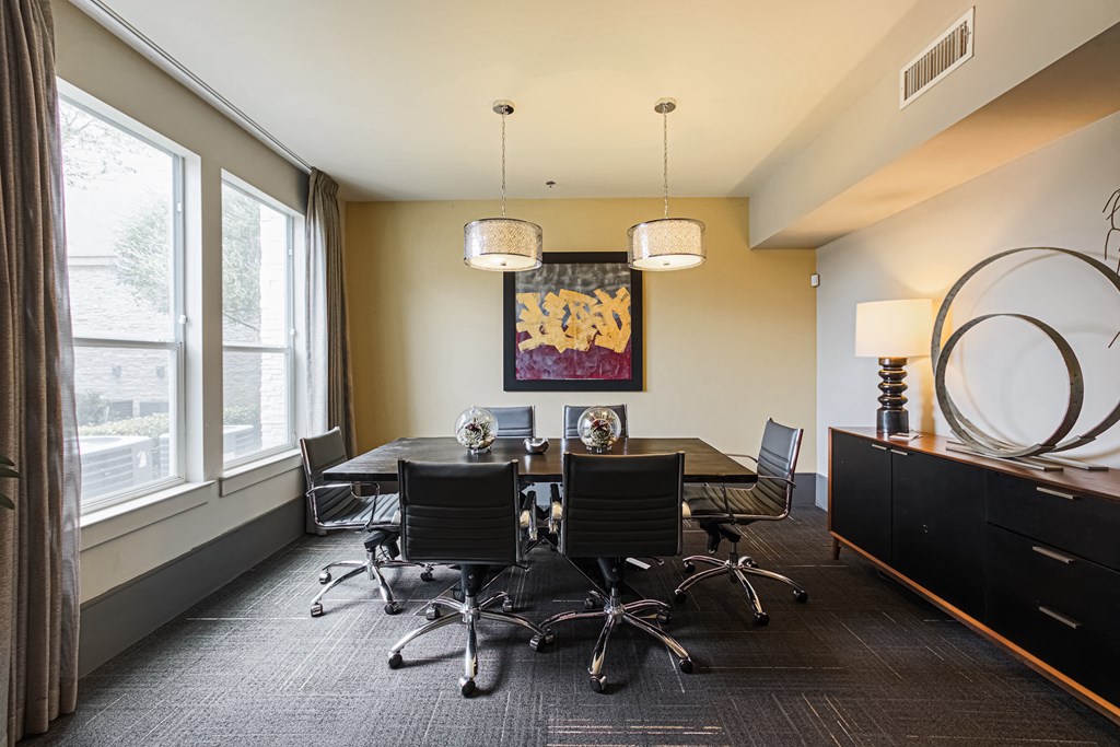 a conference room with a table and chairs and two large windows