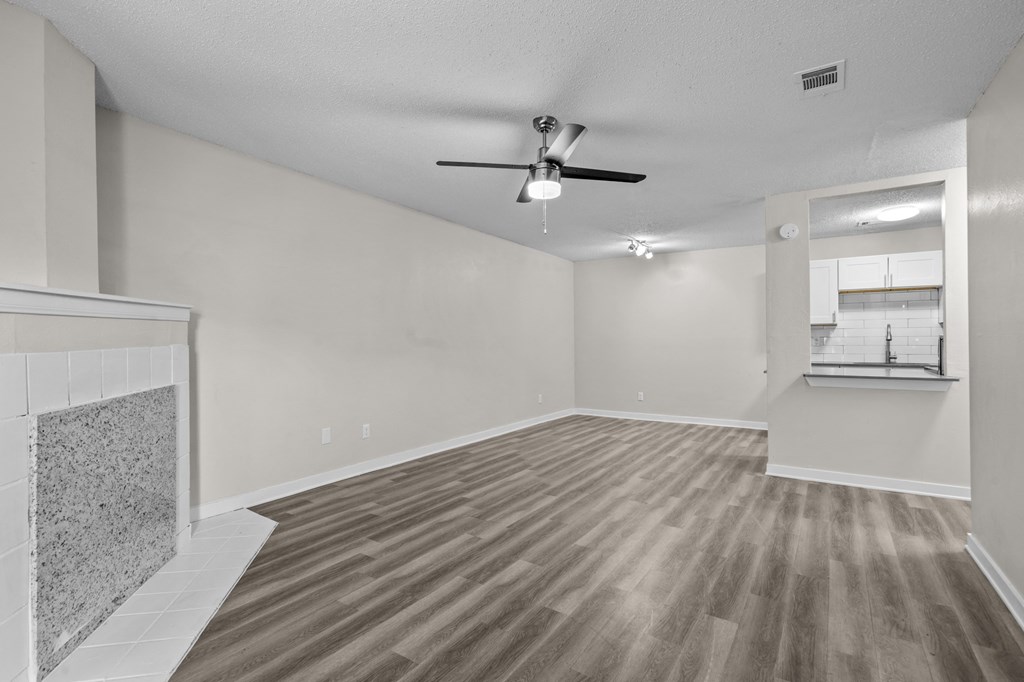 an empty living room with a ceiling fan and a fireplace