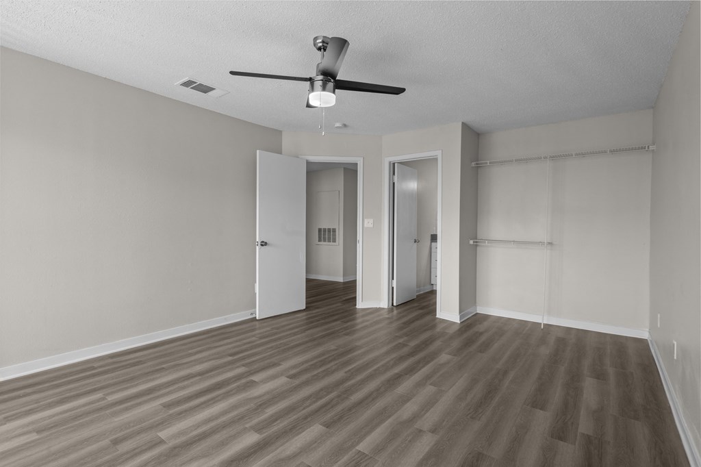 an empty living room with wood flooring and a ceiling fan