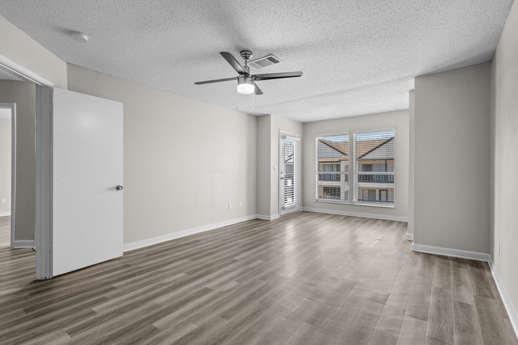 an empty living room with a ceiling fan and a window