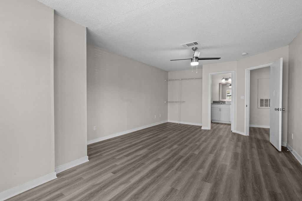 an empty living room with wood flooring and a ceiling fan
