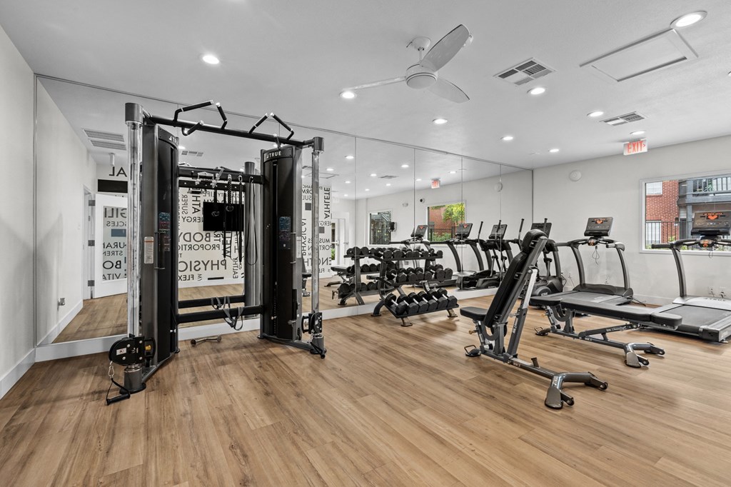 a gym with treadmills and other exercise equipment on a wooden floor