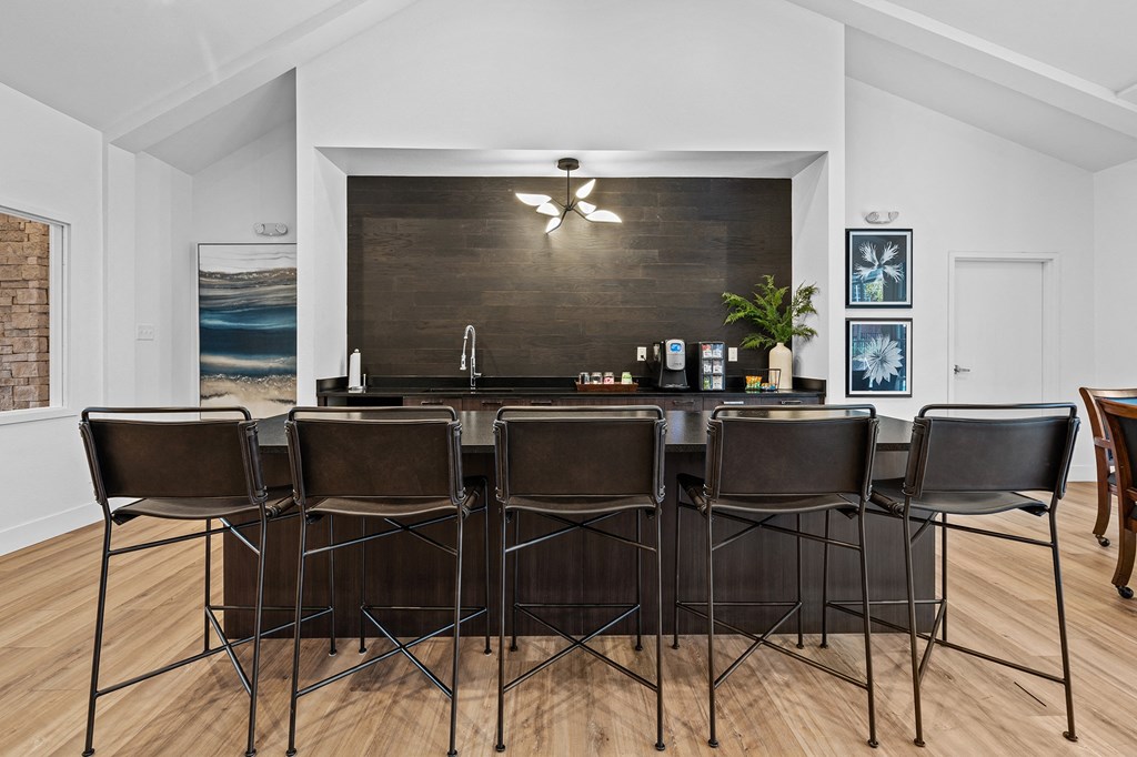 a kitchen with a bar and chairs in front of a wood floor