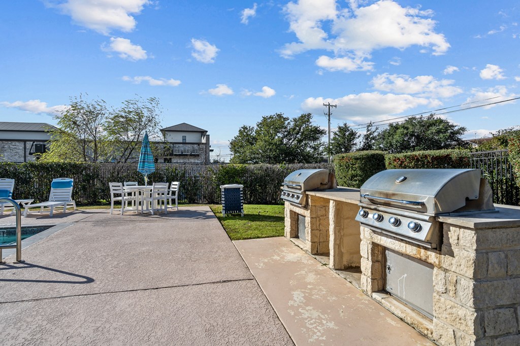 a patio with a barbecue grill and a table and chairs