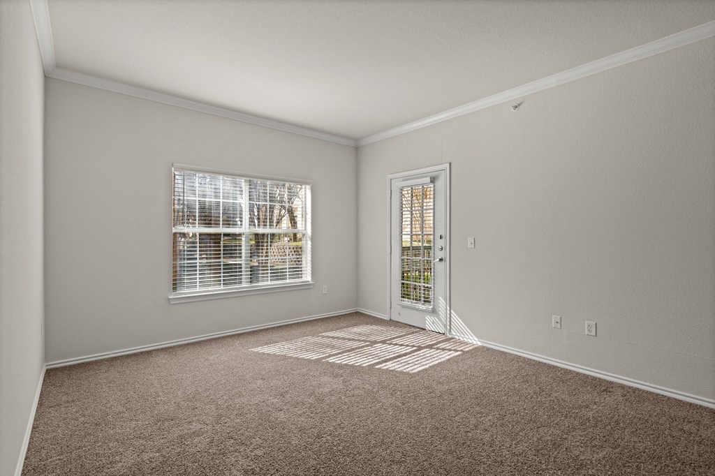 an empty room with carpet and a door to a window