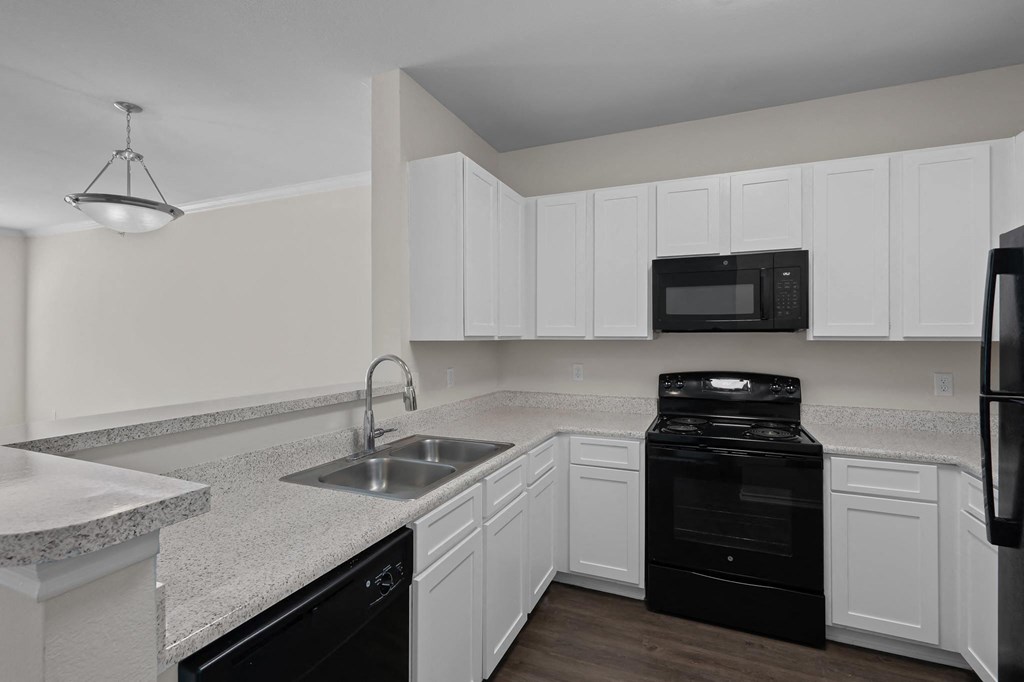 a kitchen with white cabinets and black appliances