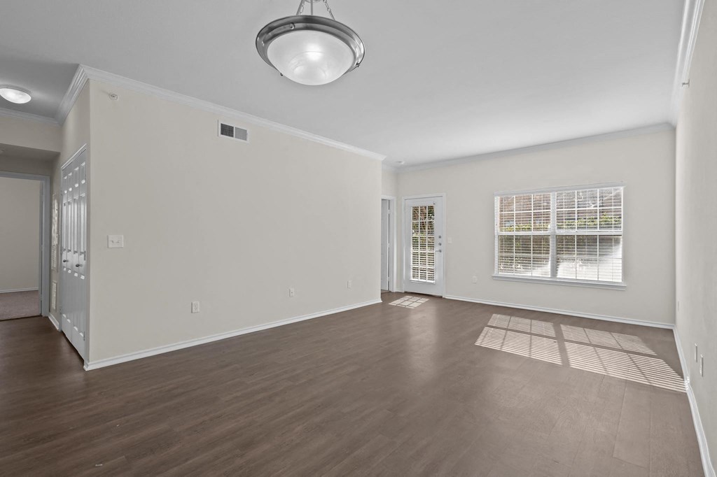 the living room and dining room of an empty house with wood floors and a window