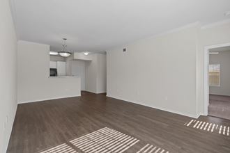 an empty living room with a hard wood floor and a kitchen