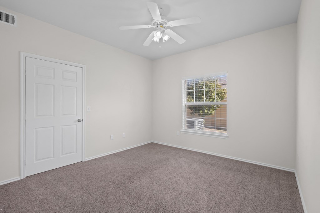 an empty bedroom with a ceiling fan and a window