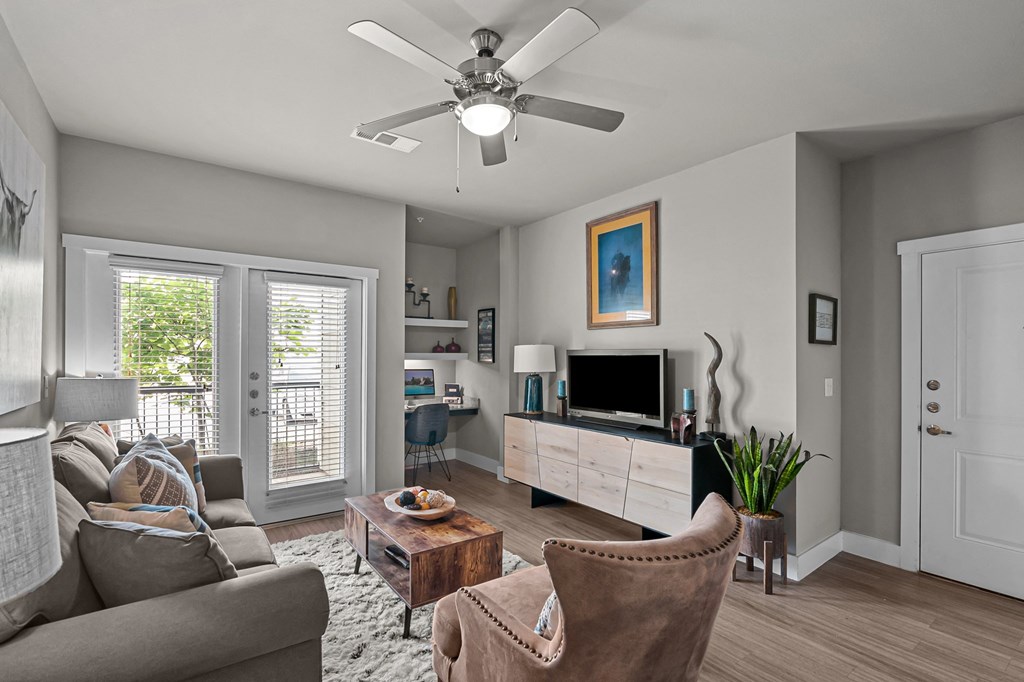 a living room with a ceiling fan and a tv