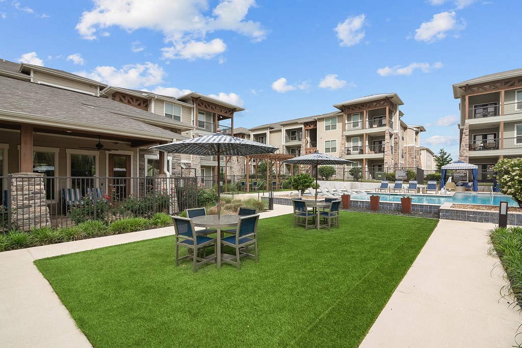 a backyard with tables and chairs and a pool with umbrellas