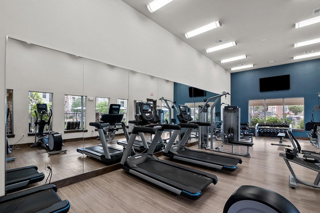 a gym with cardio equipment and weights on a wood floor