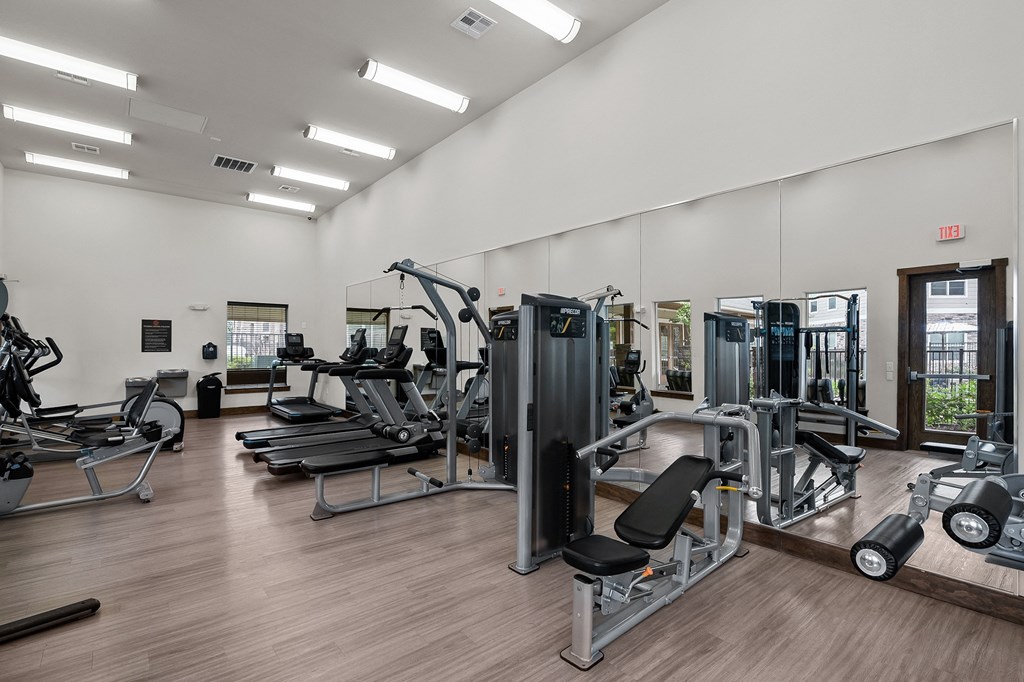 a gym with cardio equipment and mirrors on the wall