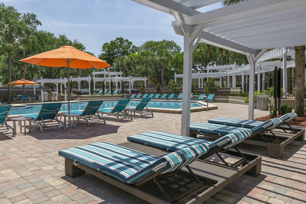 a pool area with lounge chairs and umbrellas