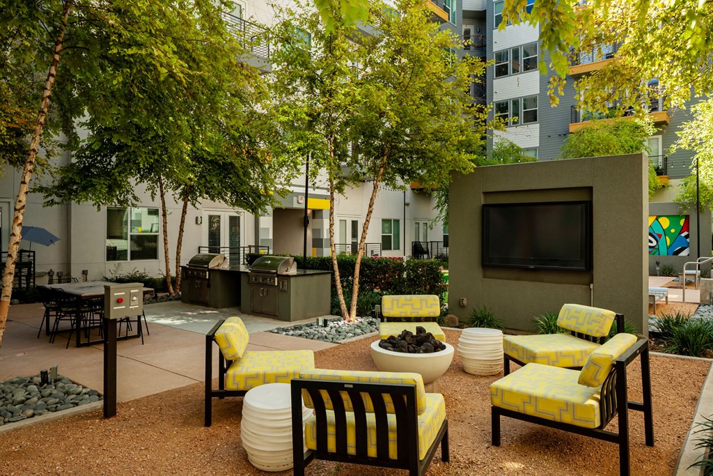 a courtyard with yellow chairs and trees and a television
