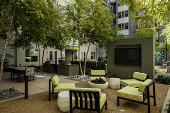 a courtyard with trees and lounge chairs and a flat screen tv