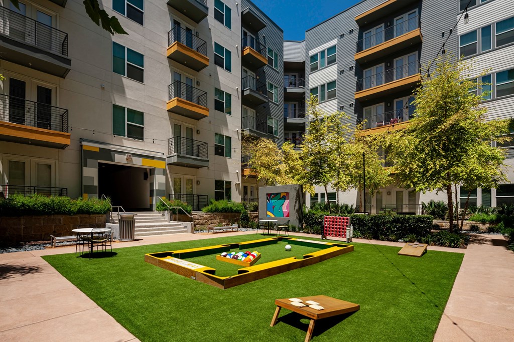 a playground in the middle of an apartment complex with a game on the grass