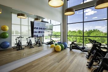 a gym with weights and other exercise equipment and large windows with a view of the city