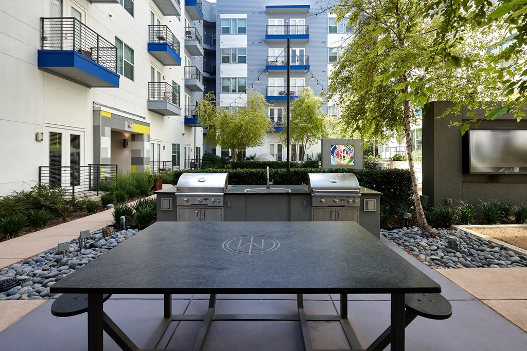 an outdoor table with two grills in front of an apartment building