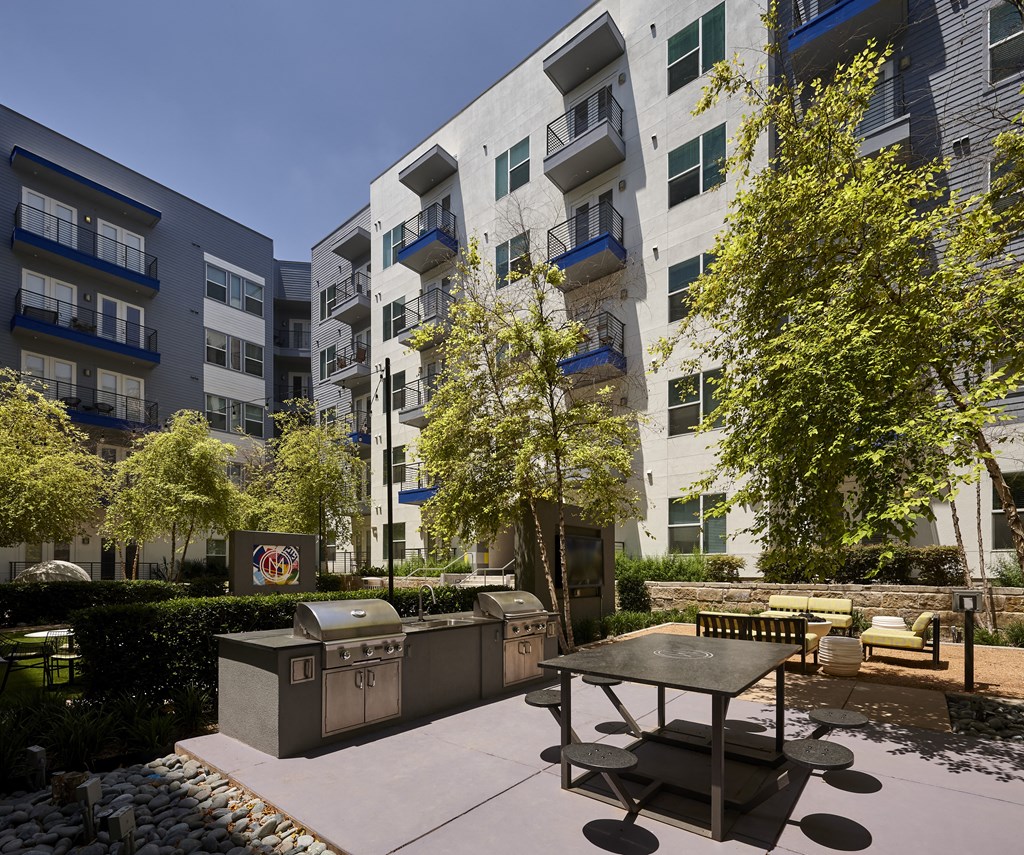 an outdoor patio with a picnic table in front of an apartment building
