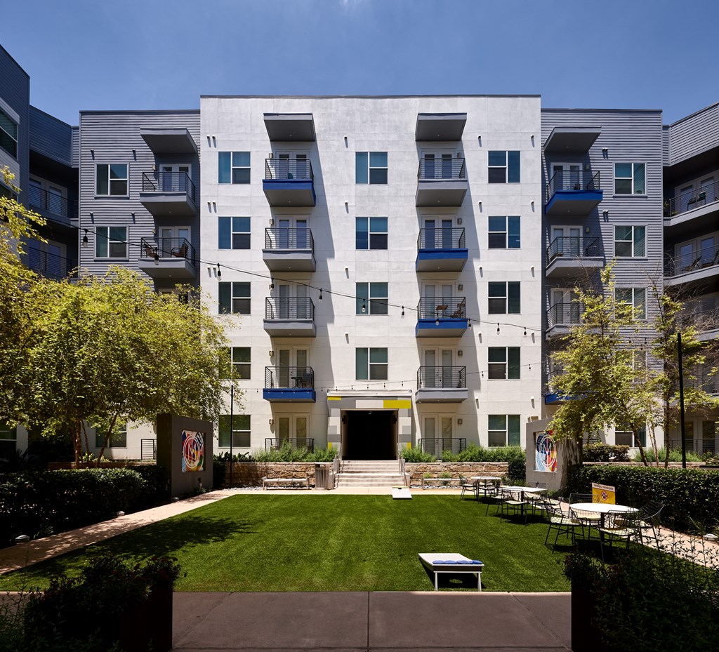 an exterior view of an apartment building with a lawn