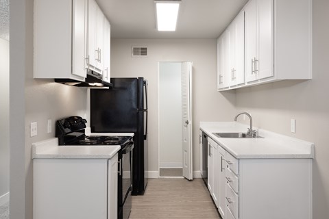 A kitchen with white cabinets and a black refrigerator.
