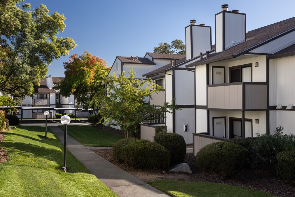A white building with a black roof and a sign on the lawn.