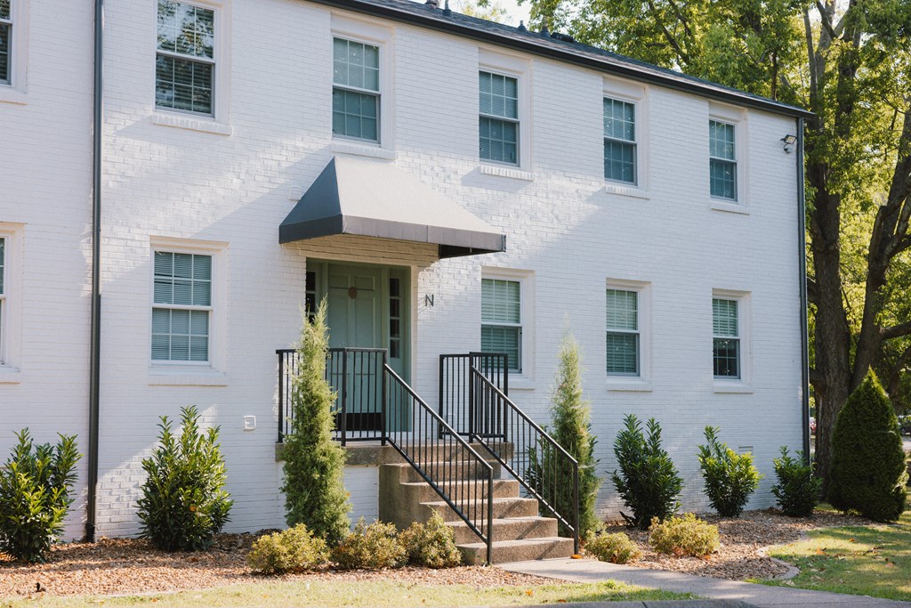 A white building with a black railing and a small porch.