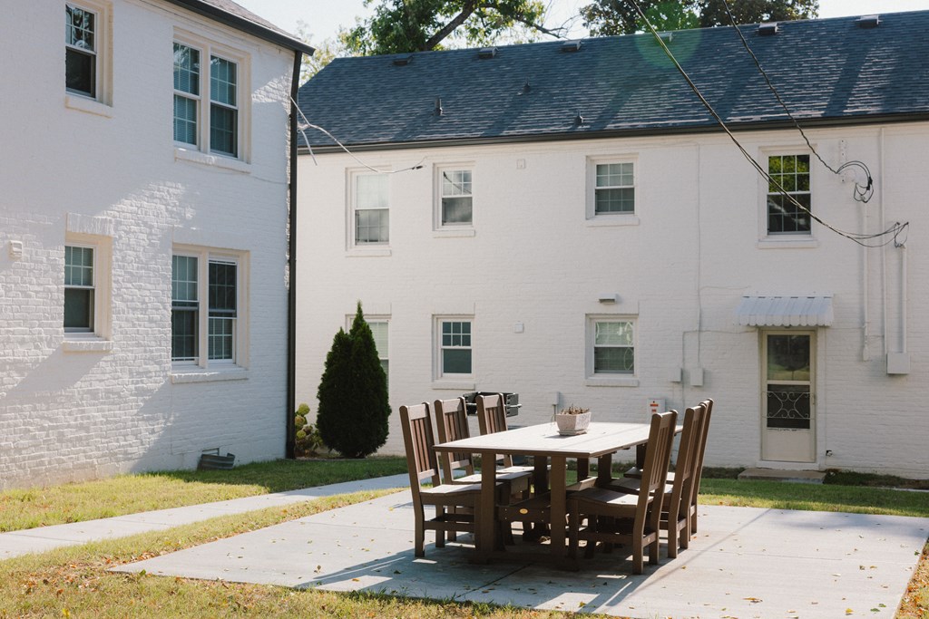 A white house with a table and chairs in front.