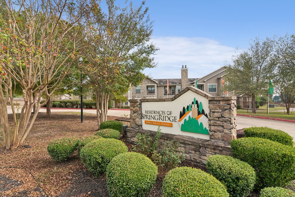 A sign for the residents of Springridge in front of a building and trees.